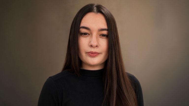 Daniela Moaca, Senior Manager IT en EOS Romania, fotografía de retrato con un suéter de cuello alto oscuro.