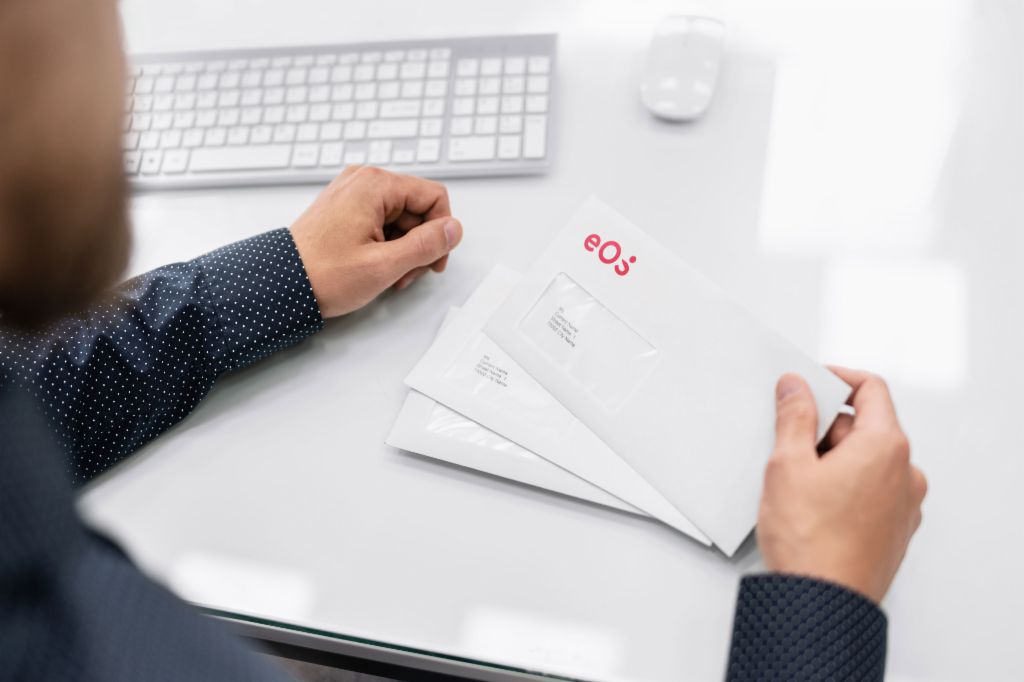 Man sitting at his desk and holding an EOS envelope in his hand.