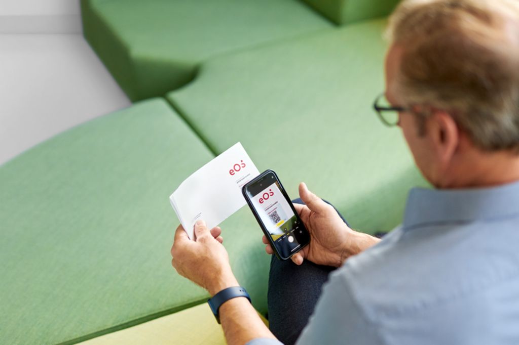 Un hombre escanea un código QR en una carta de EOS con su teléfono inteligente para pagar su reclamación pendiente en línea en el Portal EOS.