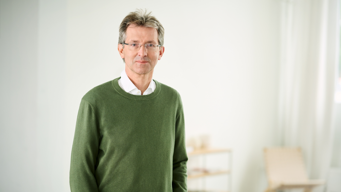 Justus Hecking-Veltman, CFO con un jersey verde bosque y una camisa blanca de pie en una estancia luminosa.