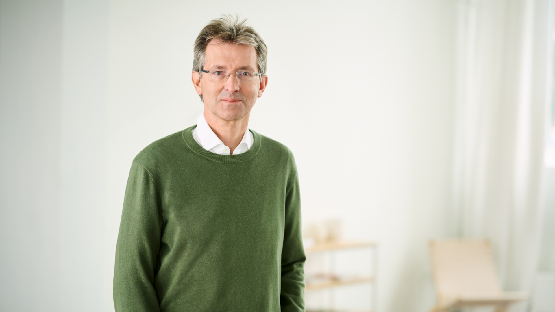 Justus Hecking-Veltman, CFO con un jersey verde bosque y una camisa blanca de pie en una estancia luminosa.