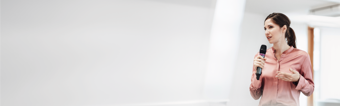 Woman with dark hair speaking into a microphone at an event