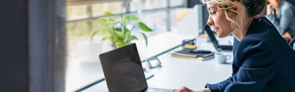 Una mujer joven trabaja en un portátil en una oficina moderna.