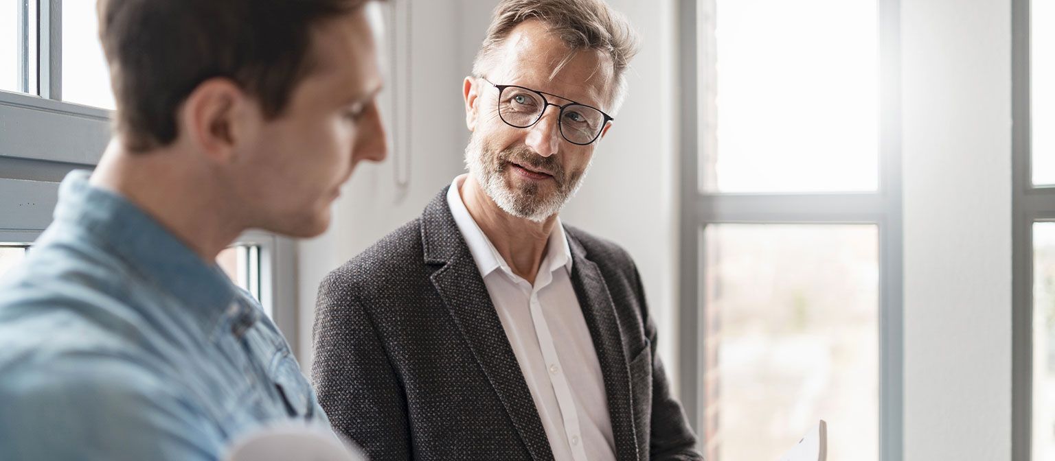 Dos hombres en una oficina discuten los resultados del estudio "Prácticas de Pago Europeas 2025" del Grupo EOS sobre la digitalización en la gestión de cobros.