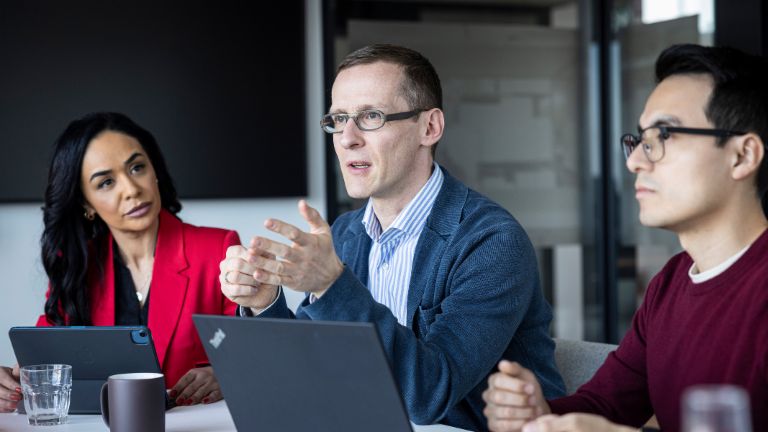 Tres personas mantienen una conversación en una oficina.